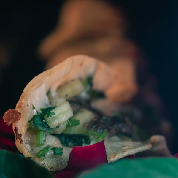 Close-up of a Machetes Gourmet taco filled with meat, cilantro, and diced onions.